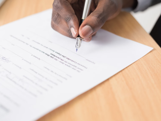 A hand holding a fountain pen filling in a survey.