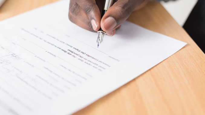 A hand holding a fountain pen filling in a survey.